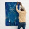 A man hanging up an art work on the wall.