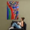 A woman sitting on the couch in front of a painting.