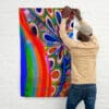 A man hanging up a painting on the wall