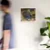 A man walking in front of a white wall with a painting on the wall.