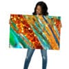 A woman holding up an art work with orange and blue stripes.
