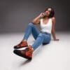 A woman sitting on the ground wearing sneakers.