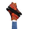 A person is holding their hand up to the top of a pair of shoes.