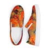 A pair of shoes with an orange and red painting on them.