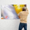 A man is hanging up a picture on the wall