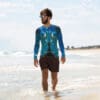 Man in ocean-themed rash guard at beach.
